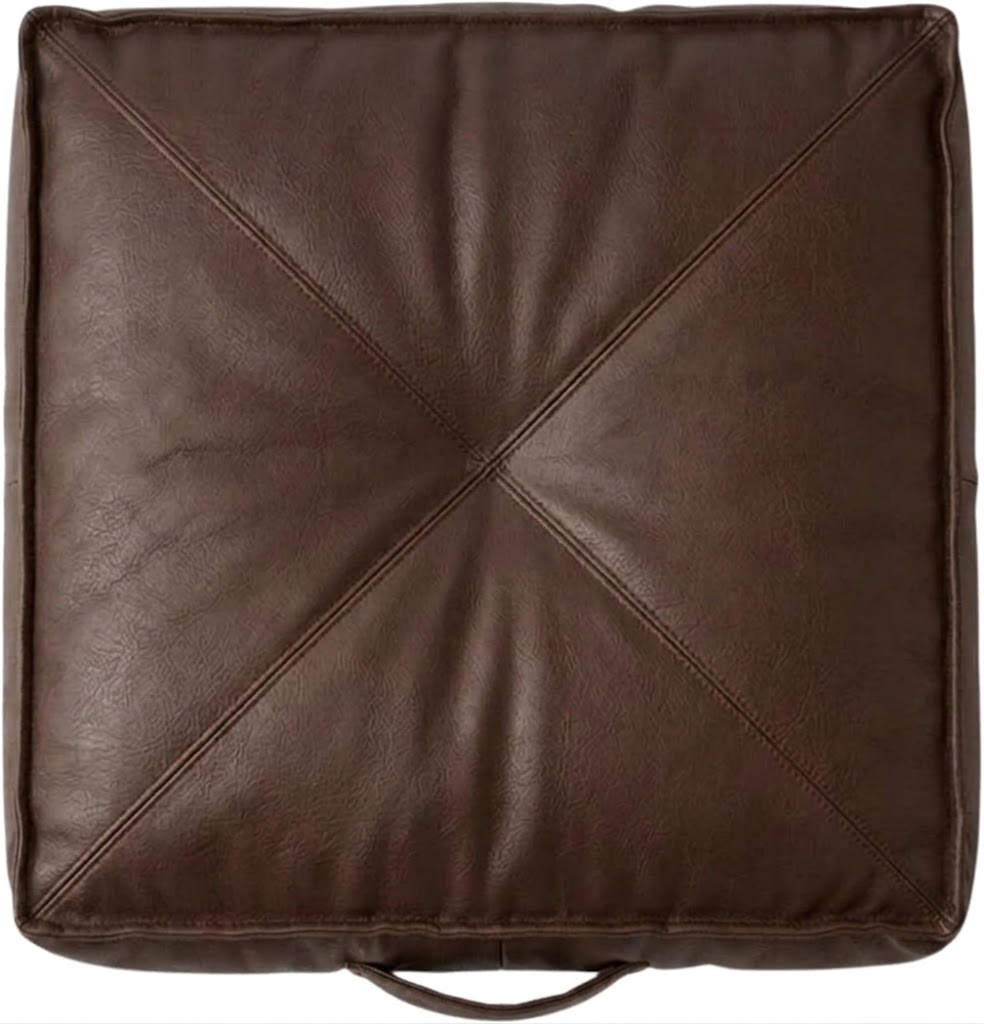 A square brown -leather floor cushion with diagonal stitched details forming an X pattern in the center and a carrying handle at the bottom, shown against a plain white background.
