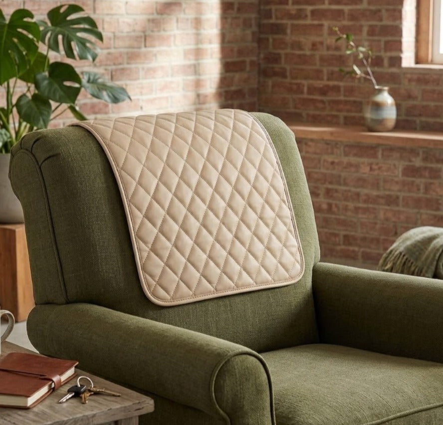 A quilted cream-colored lumbar support pillow resting on the backrest of an olive green armchair in a cozy room with a brick wall background.