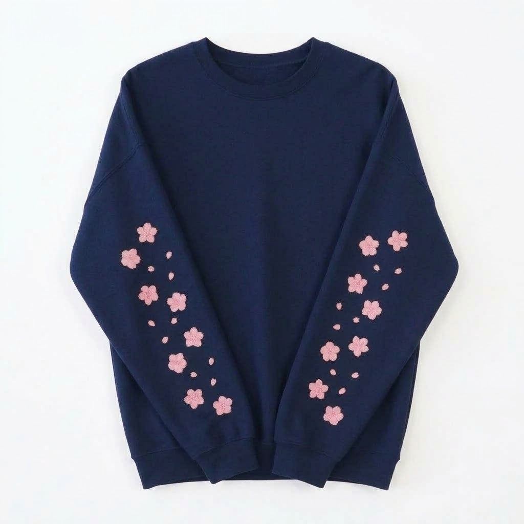 A navy blue crewneck sweatshirt with pink cherry blossom flower prints down both sleeves, laid flat against a white background.