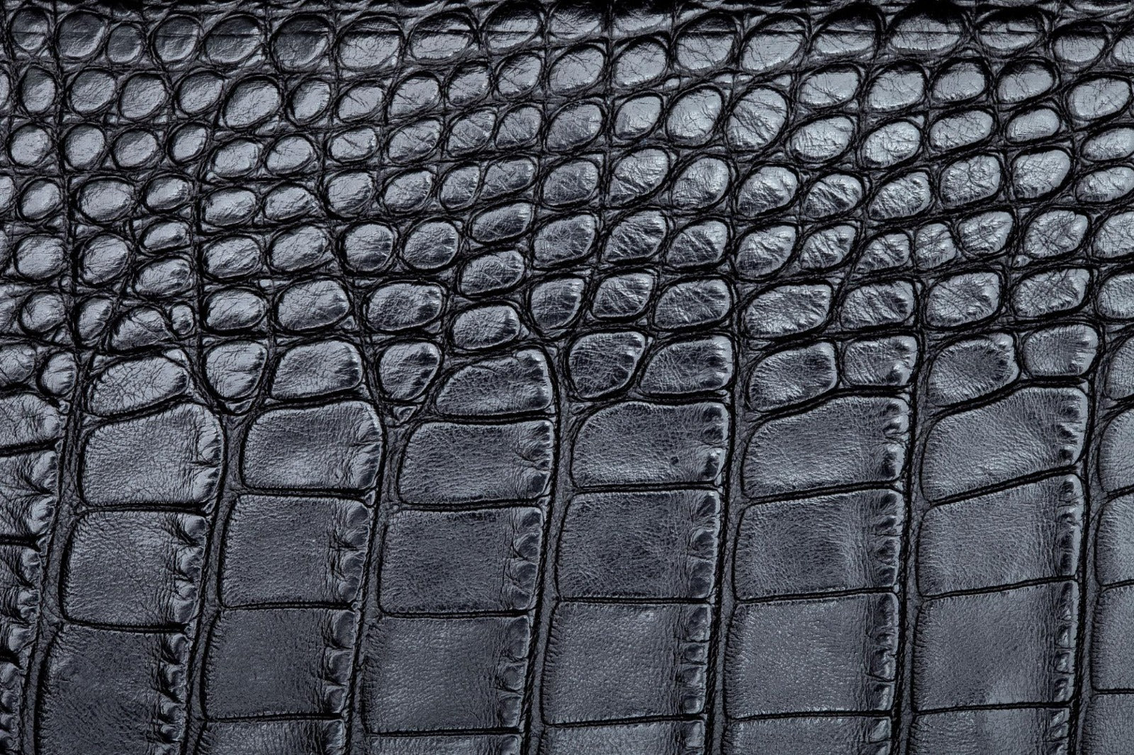 Close-up of a dark gray crocodile or alligator-textured leather surface with raised scale-like embossing and visible grain.