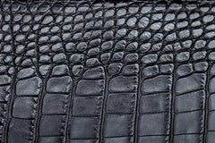 Close-up of a dark gray crocodile or alligator-textured leather surface with raised scale-like embossing and visible grain.
