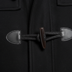 Close-up of a black duffel coat with a toggle closure, featuring a dark brown wooden toggle and black braided cord with stitched leather-like tabs.
