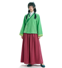 A model wearing a traditional Chinese Hanfu costume consisting of a bright green long-sleeve top with a diagonal sash and a wide, pleated magenta skirt, paired with a white collar and dark teal shoes.