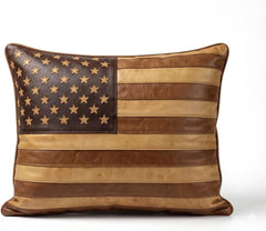 A square decorative throw pillow featuring a distressed American flag design made from layered leather panels in dark brown, tan, and medium brown, with metallic gold stars on the canton.