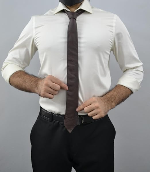 A man wearing a white long-sleeve dress shirt, a dark brown tie, and black trousers, shown from the neck down against a plain gray background.
