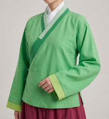 A person wearing a bright green traditional Korean Hanfu jacket with contrasting light green and white trim, paired with a dark red skirt, shown against a plain light gray background.