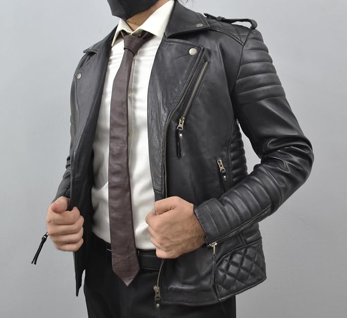 A man wearing a black leather motorcycle jacket over a white dress shirt and brown tie, shown from the neck down against a plain gray studio background.