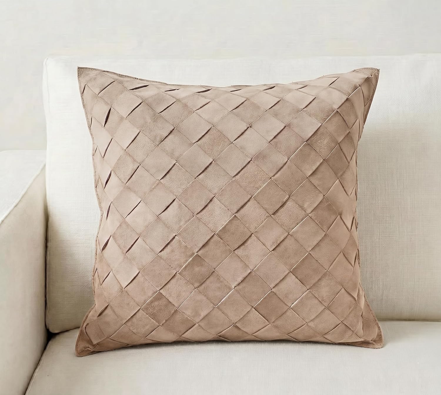 A square throw pillow in a textured taupe woven fabric, resting on a light beige sofa.