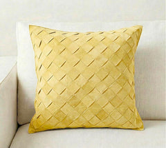 A square yellow throw pillow with a woven basketweave texture, resting on a light beige fabric sofa.