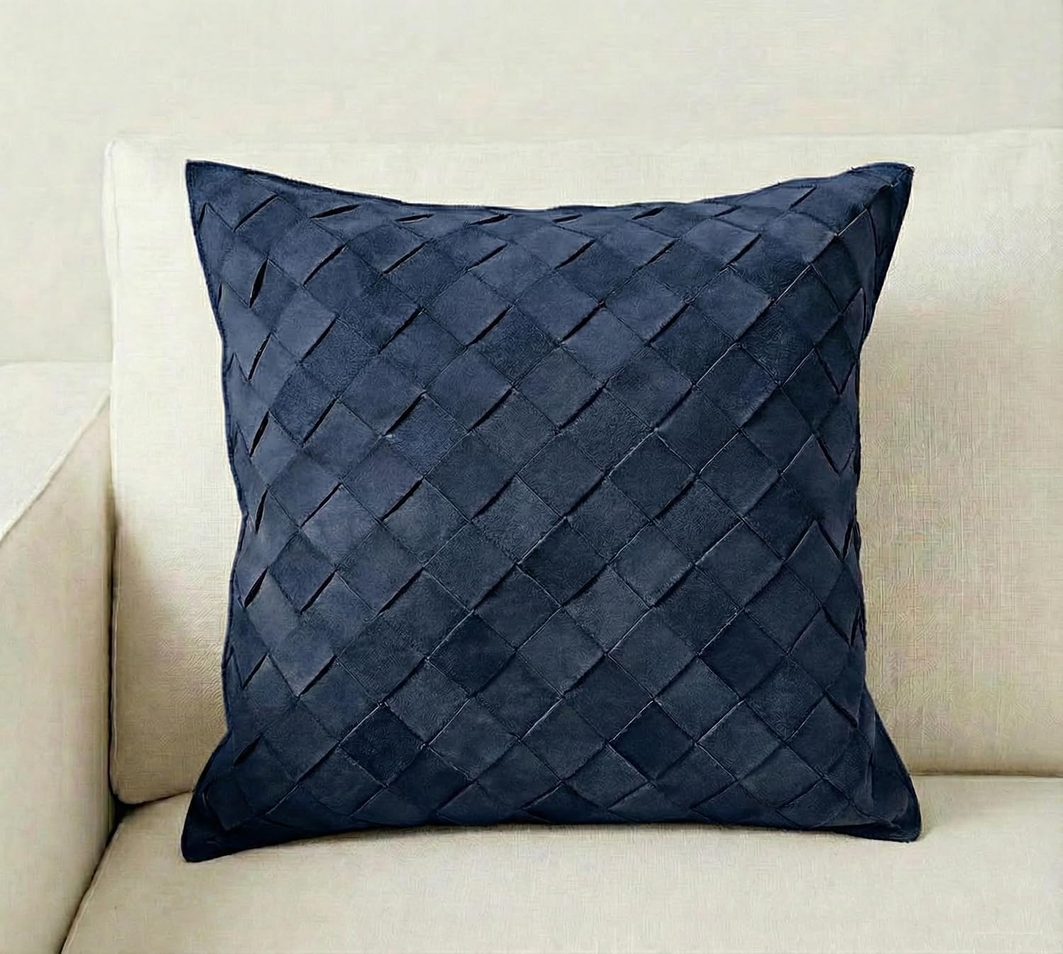 A square navy blue throw pillow with a woven basketweave texture, resting on a light beige fabric sofa.