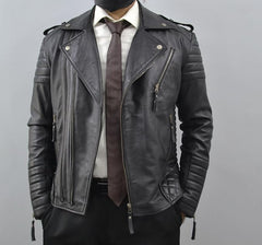 A black leather motorcycle jacket with silver zippers and quilted details, styled on a model wearing a white shirt, brown tie, and black pants against a gray background.