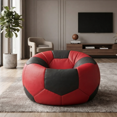 A round, soccer-ball-inspired bean bag chair in red and black faux leather, placed on a gray rug in a modern living room setting.