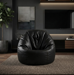 A black leather bean bag chair centered in a modern living room setting with a dark gray wall, wall art, a television, a plant, and a textured rug.