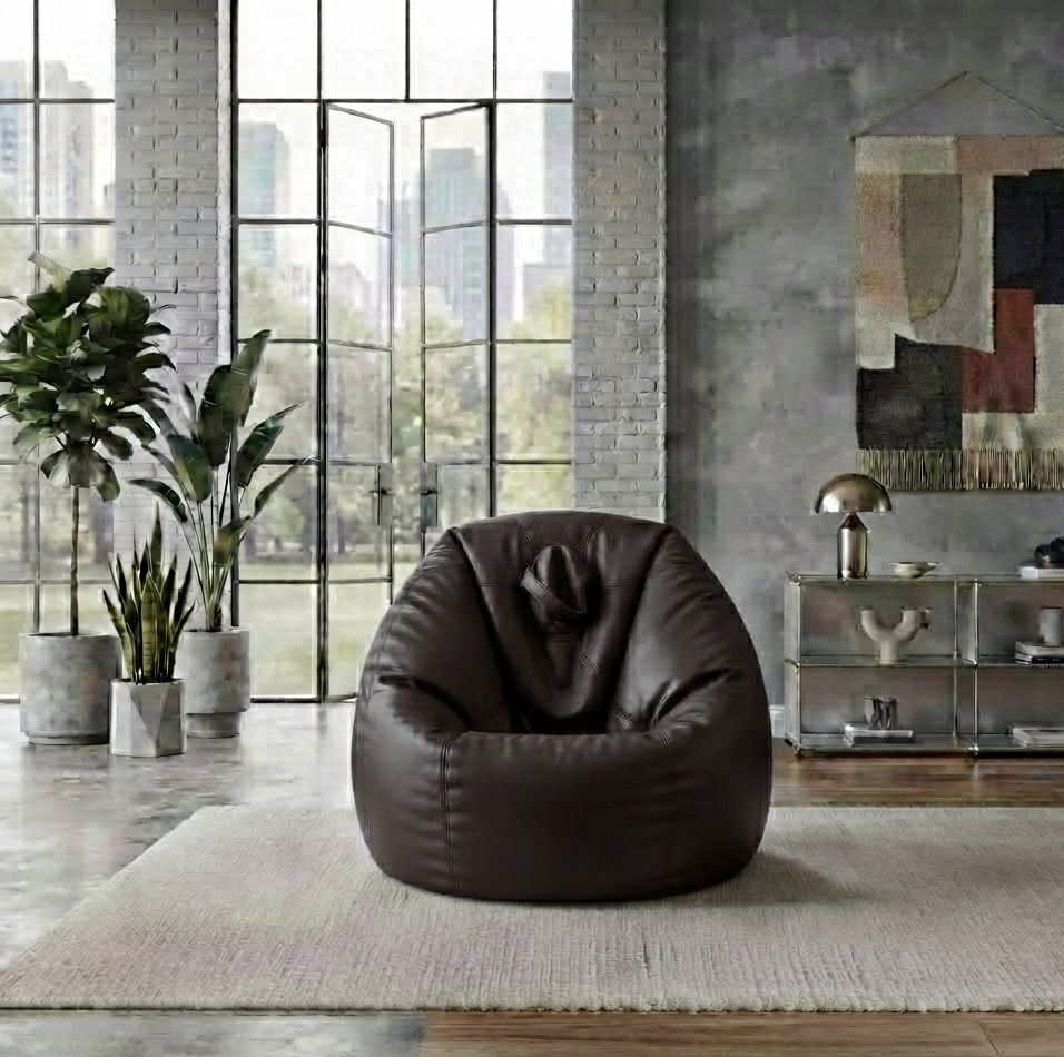 A dark brown leather bean bag chair placed on a light beige rug in a modern industrial loft room with large windows, brick walls, and plants.