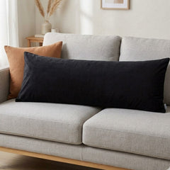 Black rectangular pillow on a gray sofa with a neutral background
