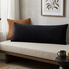 Black pillow on a beige sofa with a plant-themed painting in the background