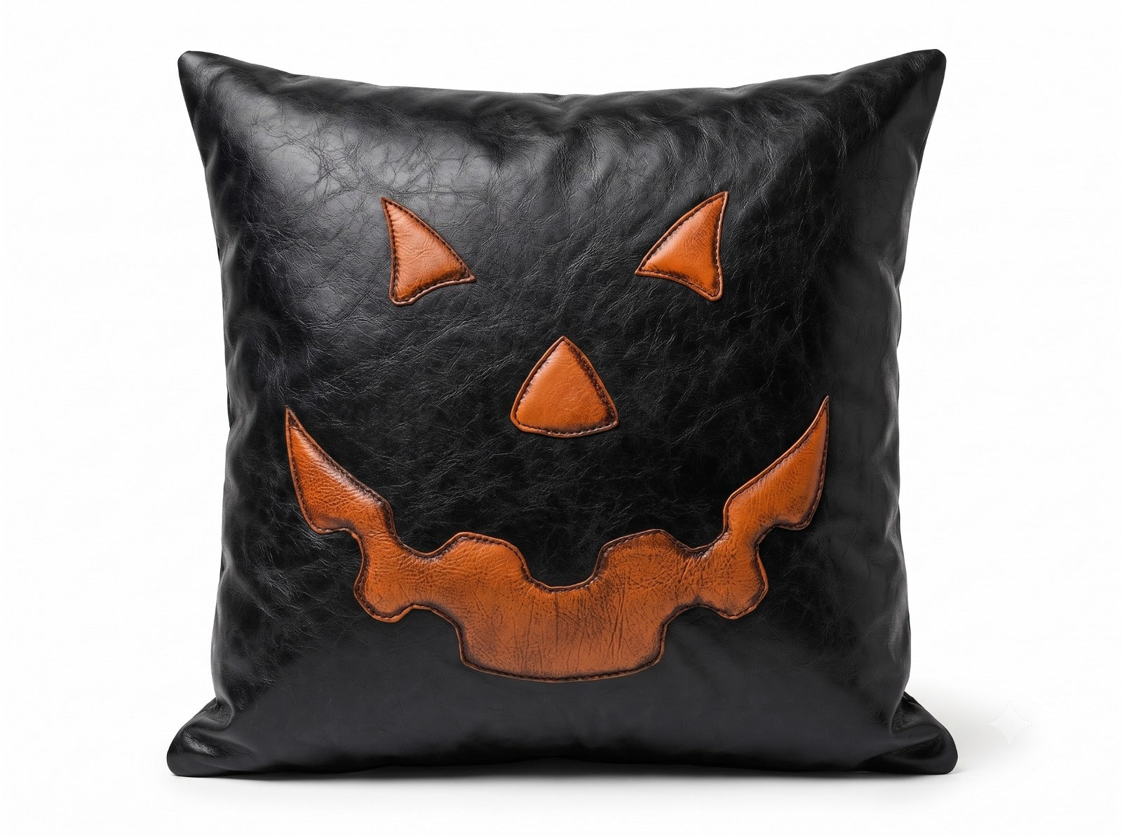 A square black -leather throw pillow featuring a stylized orange jack-o'-lantern face applique on the front, set against a plain white background.