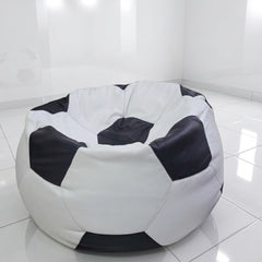 A round bean bag chair designed like a soccer ball, featuring black and white panels, set in a bright, modern white room with tiled floors.