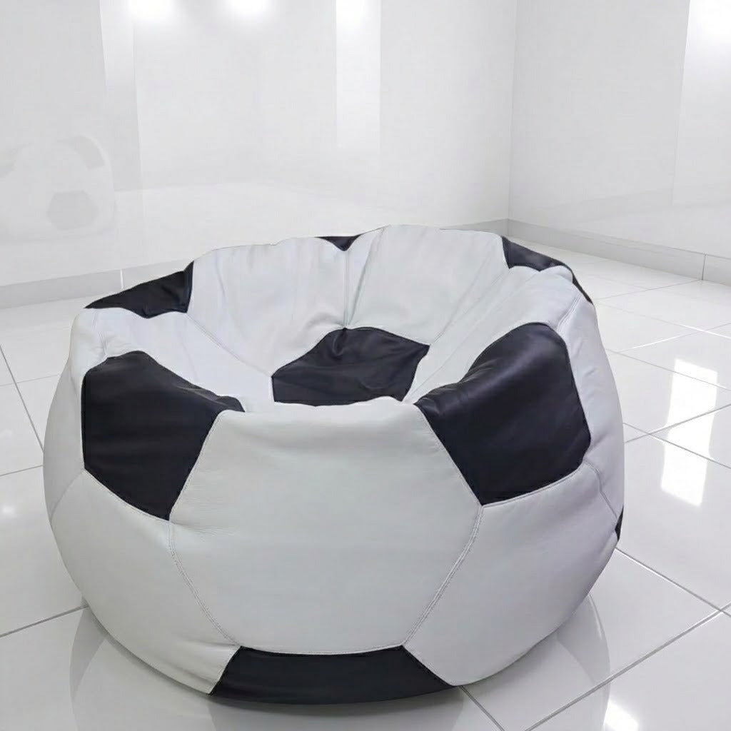 A round bean bag chair designed like a soccer ball, featuring black and white panels, placed on a glossy white tiled floor in a bright, minimalist room.