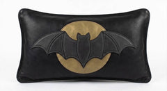 Matte black leather lumbar pillow cover featuring a dimensional bat silhouette layered over an antique gold-toned leather full moon, finished with charcoal edge stitching, shown against a white background.
