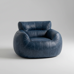 A modern round armchair upholstered in distressed navy blue leather, shown from a three-quarter angle on a light gray studio background.