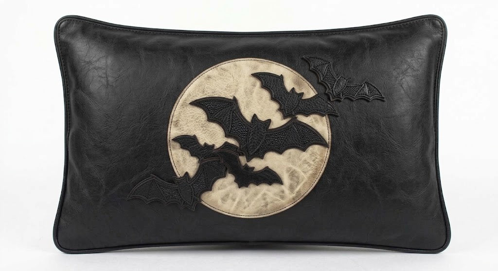 Black leather rectangular pillow with a circular beige moon patch and raised black bat appliqués on the front, shown against a plain white background.