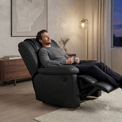 A man reclining comfortably in a black leather recliner chair in a modern living room setting with warm ambient lighting.