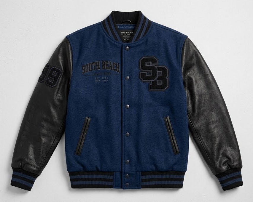 A blue and black varsity jacket with 'South Beach' and 'SB' lettering on the front, displayed flat against a light gray background.