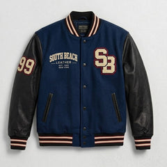 A varsity-style jacket with a navy blue body, black leather sleeves, and striped ribbed trim in beige, white, and black. The jacket features 'SOUTH BEACH LEATHER' embroidered on the left chest, 'SB' on the right chest, and '99' on the left sleeve.