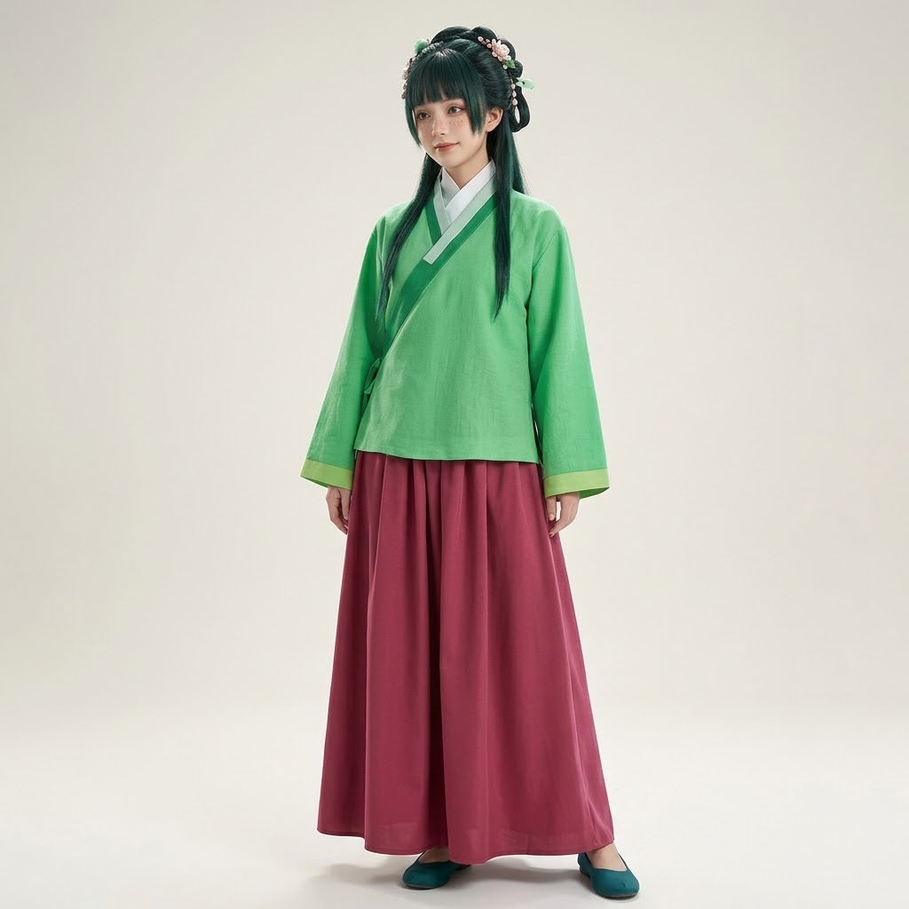 A model wearing a traditional Chinese Hanfu outfit consisting of a green short-sleeved top with a diagonal collar, a deep magenta wide-leg skirt, and teal shoes, standing against a plain light beige studio background.