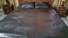 A king-size black leather bed sheet with a square pattern, laid on a bed with two black pillowcases.